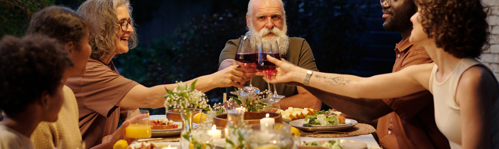 An outdoor summer dinner party with guests toasting with wine glasses