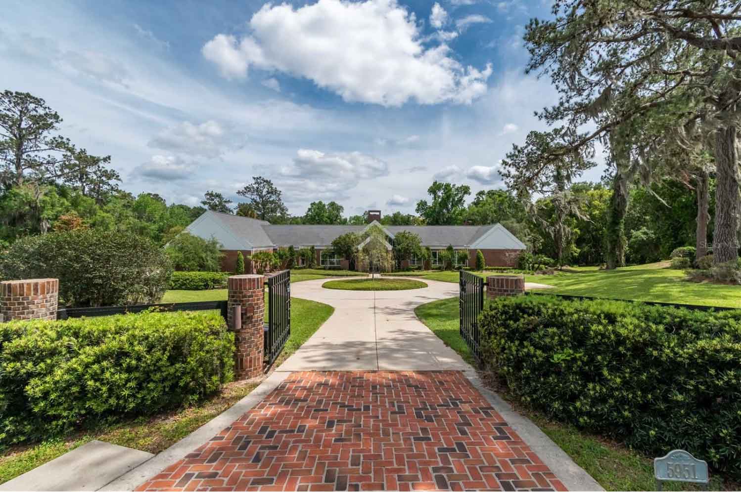 A luxurious pool area with plenty of room for seating, an attached hot tub and covered outdoor kitchen.